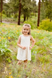 little girl in field of flowers looking at camera
