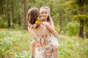 girl holding bouquet as she is being held by her mom