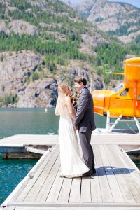 stehekin elopement couple standing together on dock in from of orange plane