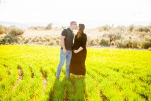 husband and wife stand side by side in glowing green east wenatchee field