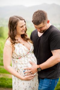 couple laughing as husband holds wife's belly