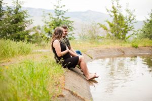 couple sitting with feet in water and mountain range behind