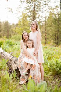 three generations of women embracing on log during golden hour