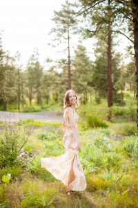 woman in floral dress twirling in light coming through the trees